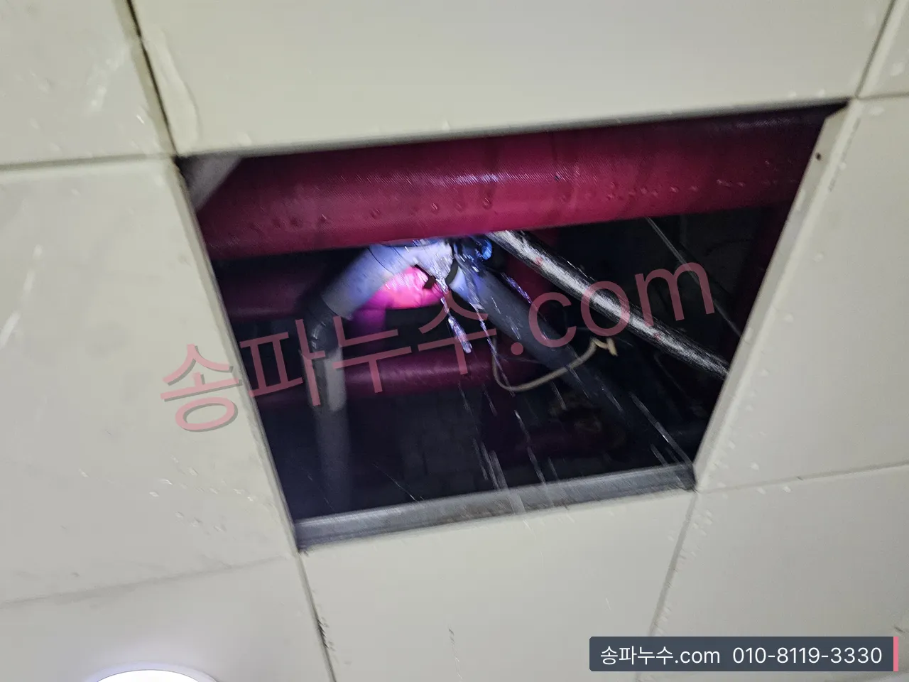 천장 점검구를 열어 보온재 배관을 손전등으로 비춘 장면