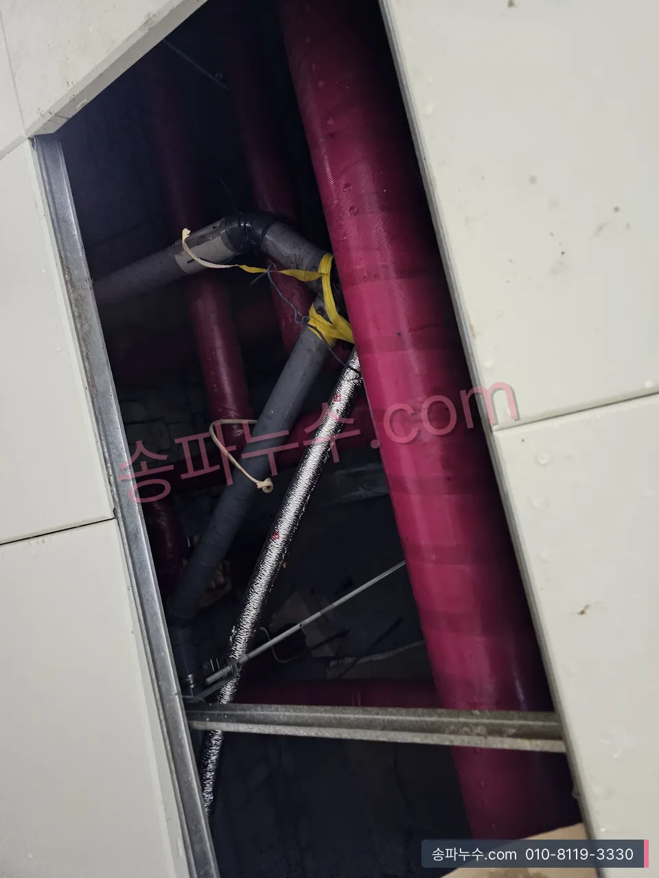 점검구 안 보온 배관 이음을 손으로 확인하는 근접