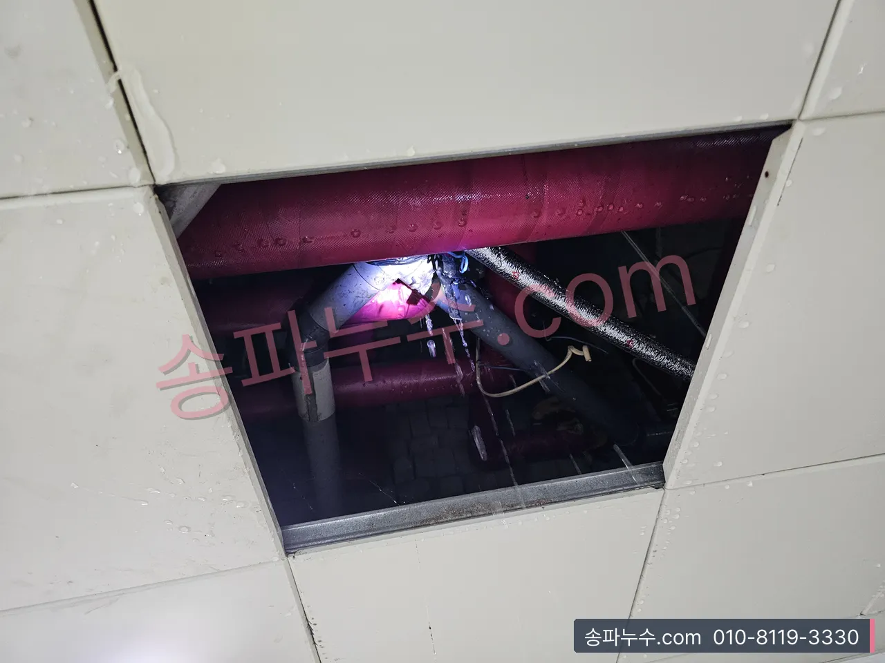 천장 점검구 안 배관 이음에서 물이 뿜어 나오는 장면