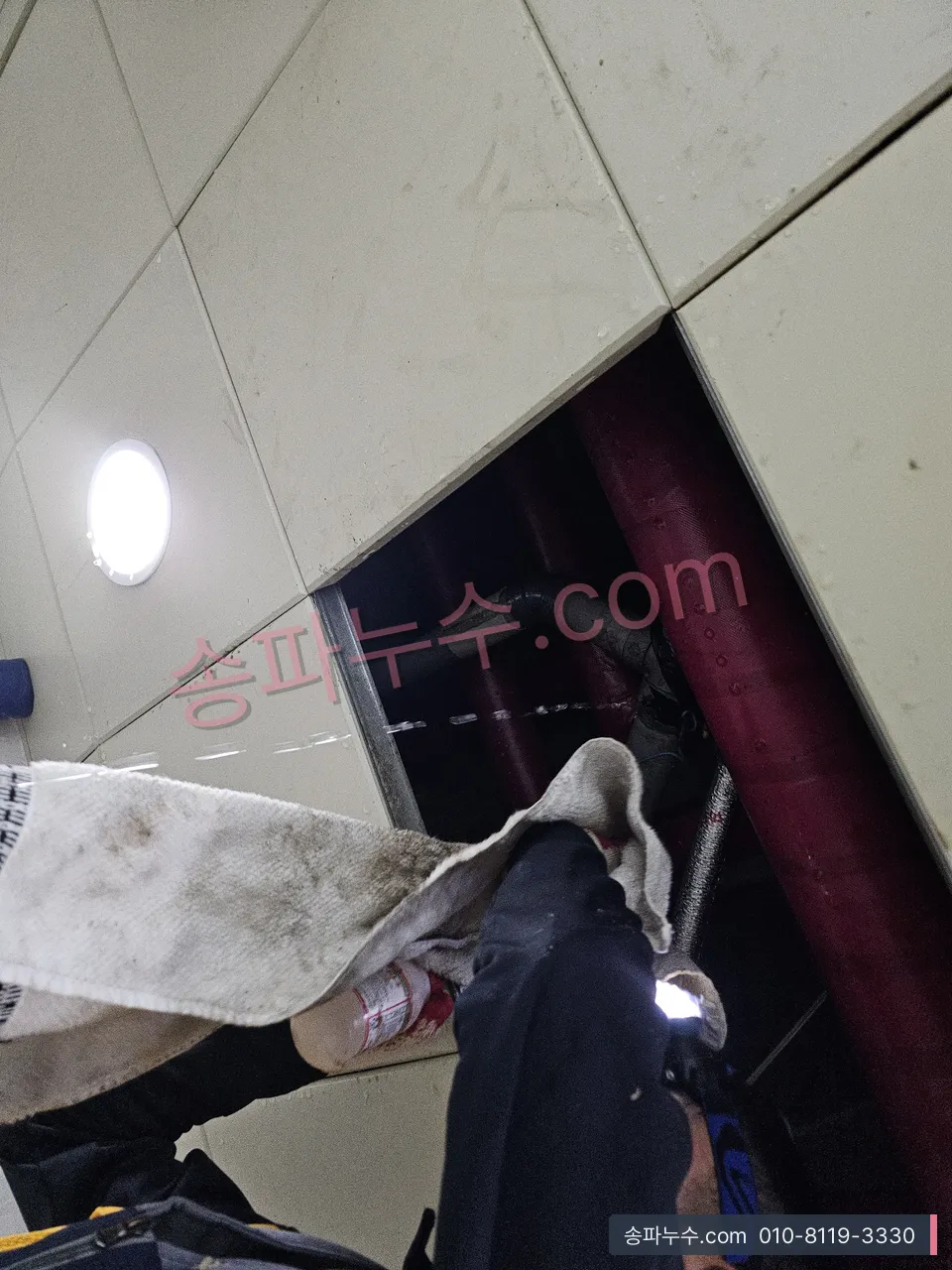 천장 점검구 주변 젖은 마감을 걸레로 받치며 확인하는 장면