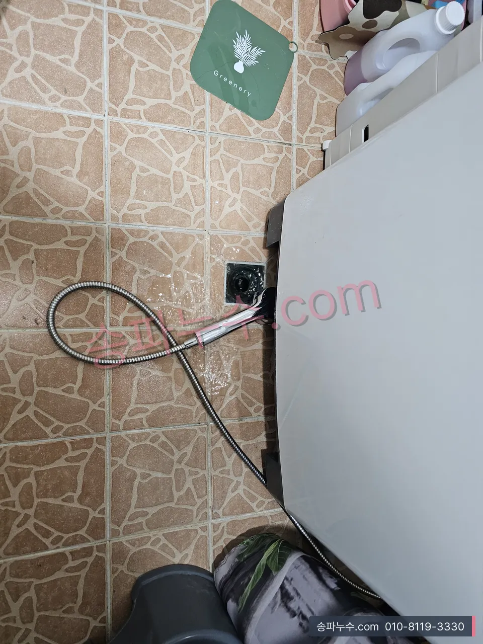 세탁기 뒤로 이어지는 배수 호스와 바닥 배수구